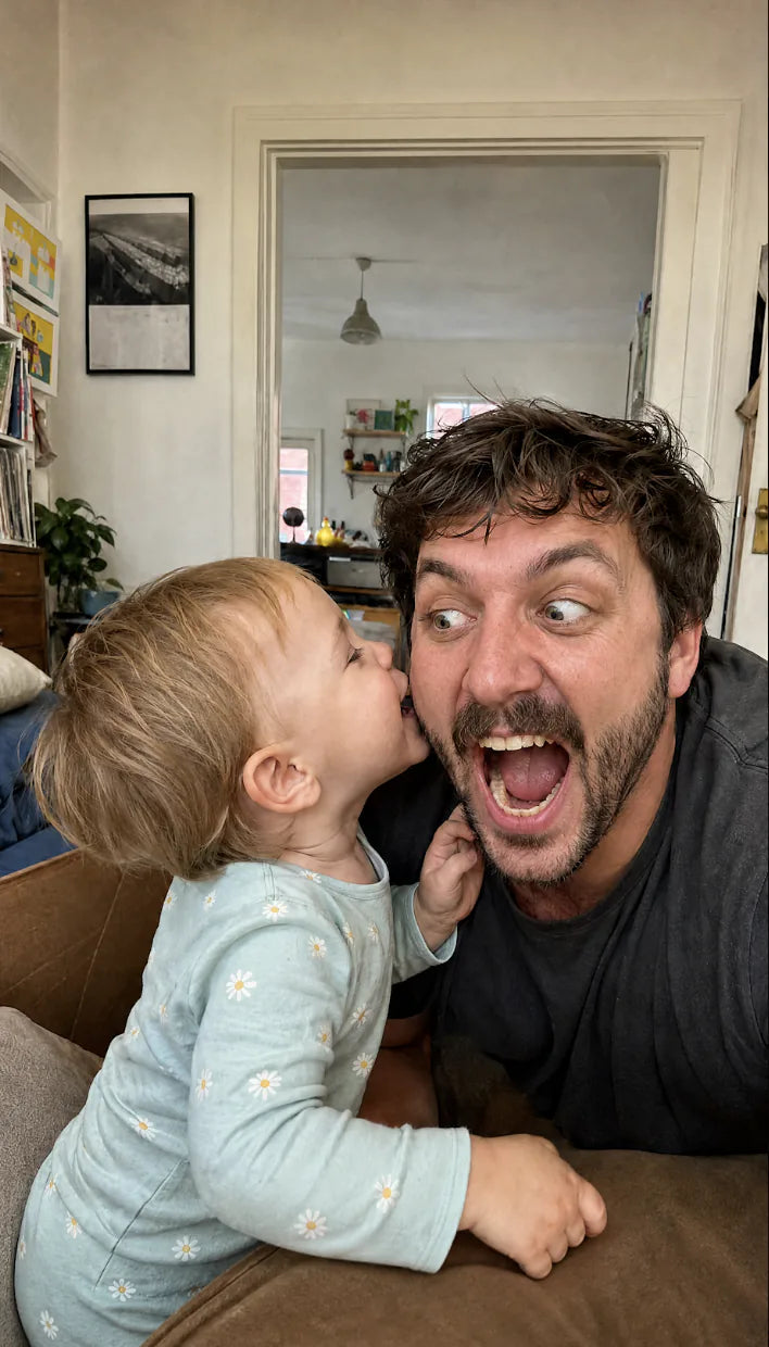 Toddler kisses dad's cheek while dad pulls an exaggerated screaming face