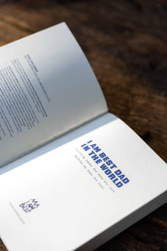 Open I Am Best Dad In The World book showing the blue title page on a dark wooden table